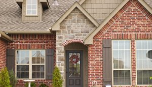 Home with brick and stone siding and large windows with brown shutters